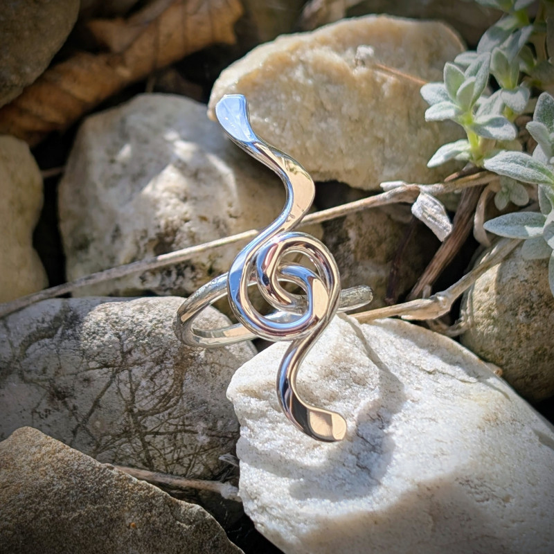 Bague Mélodie Goupil Bijoux d'Art en argent massif, motif clé de sol stylisée, posée sur des roches claires