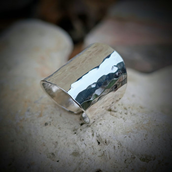 Plan rapproché sur la texture unique de l'argent martelé et le jeu de lumière.