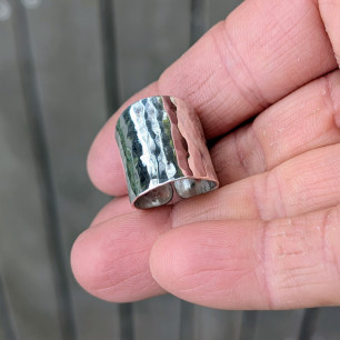 La bague large L'Empreinte de l'Artisan tenue dans la paume (vue taille).